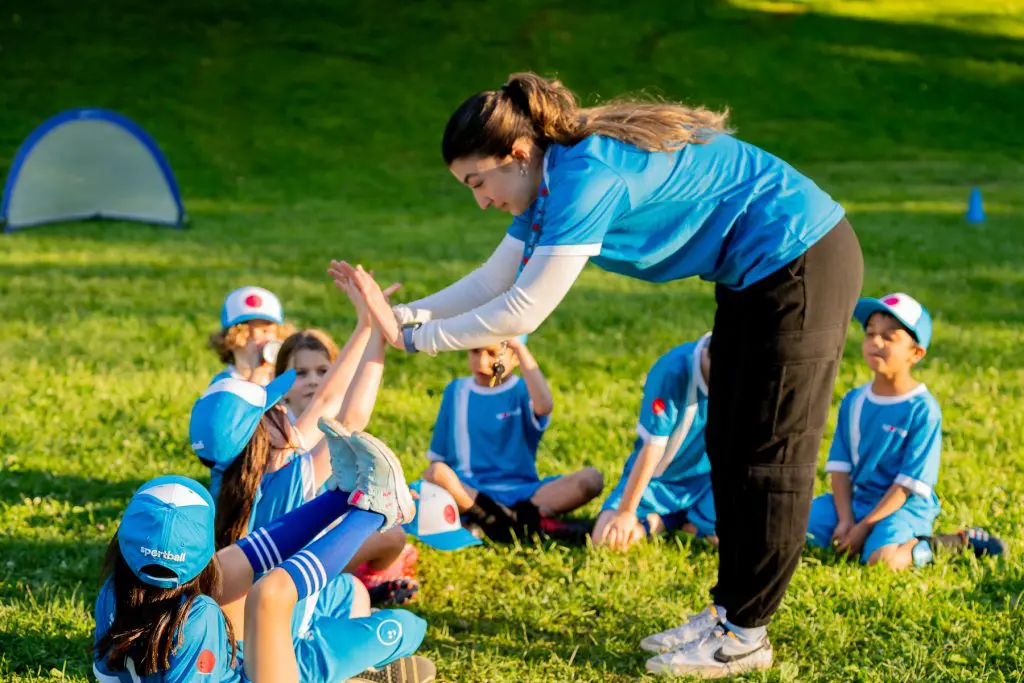 Kids soccer coach encouraging child with other children looking on